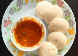 a white plate topped with three dumplings and a bowl of sauce