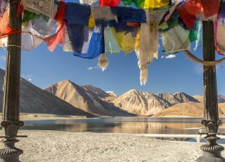 blue yellow and red textile on gray sand near lake and mountain during daytime