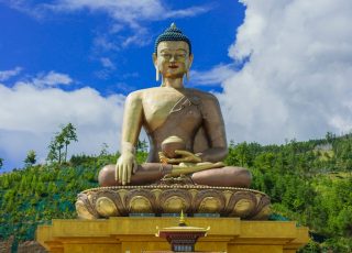 a large buddha statue sitting on top of a fountain